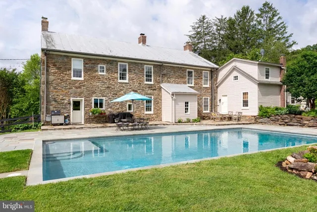 a view of a swimming pool with a yard and large trees
