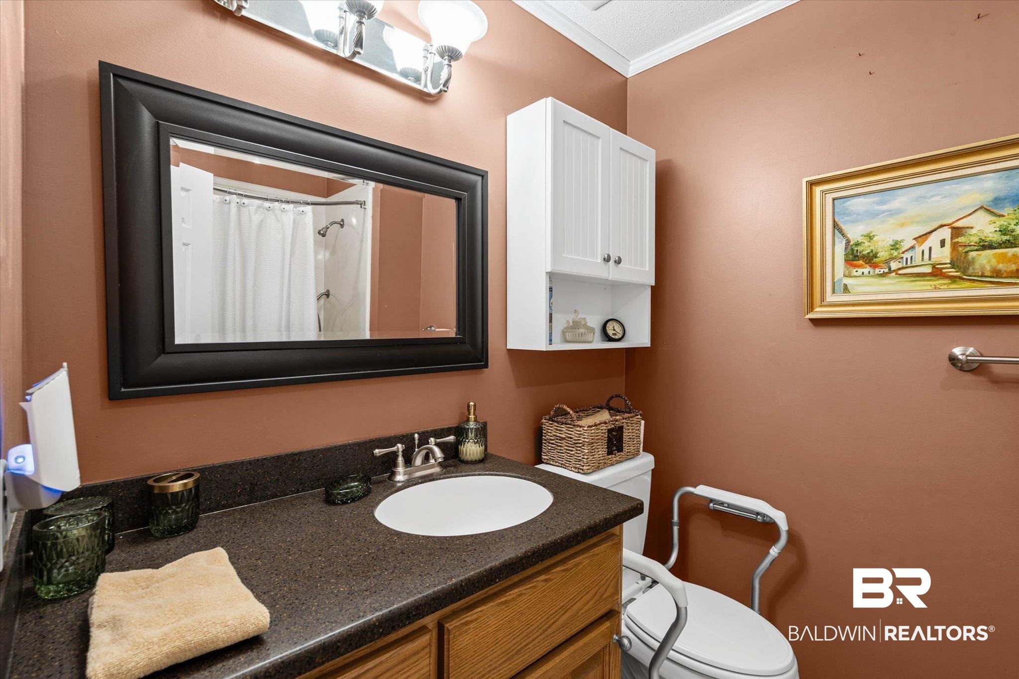 7410 Smithfield Road East Mobile, AL 36695 - Photo 15 of 24 Bathroom featuring a dark countertop with an integrated white sink, wood-finish vanity cabinetry, and a large framed mirror