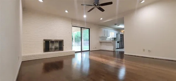 an empty room with wooden floor a fireplace and windows