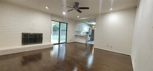 an empty room with wooden floor fireplace and windows