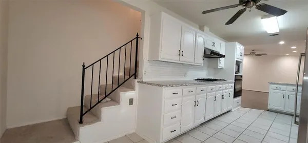 a kitchen with stainless steel appliances granite countertop a refrigerator sink and white cabinets