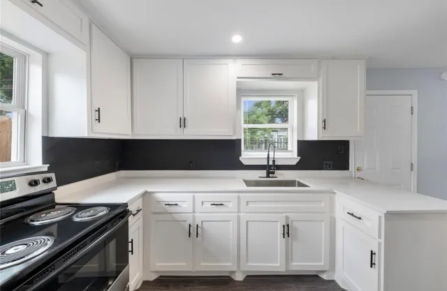 a kitchen with granite countertop white cabinets and a stove top oven