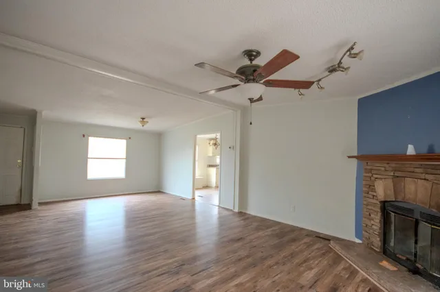 an empty room with wooden floor a ceiling fan and a fireplace