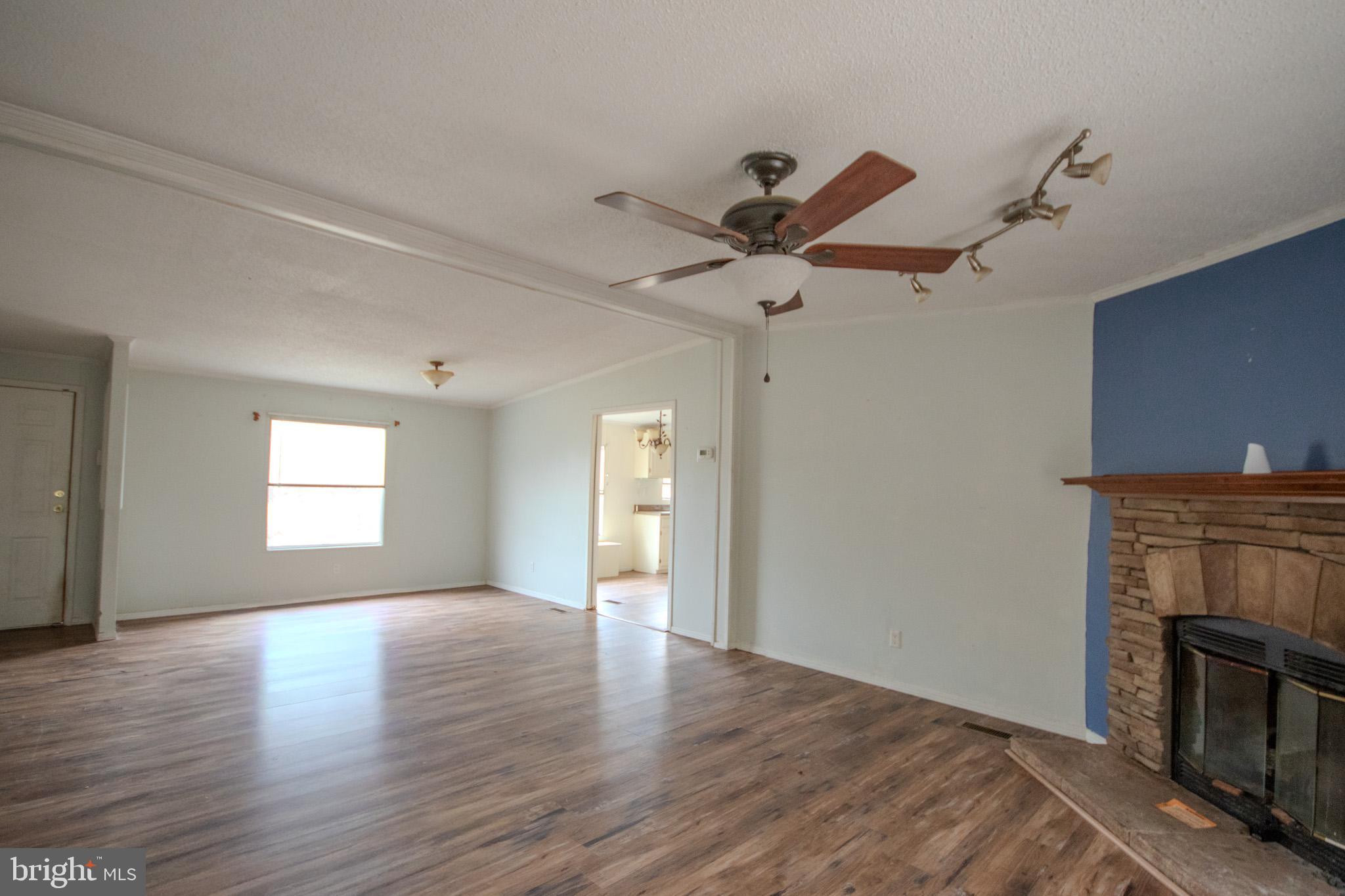 3887 Texas Road Bivalve, MD 21814 - Photo 8 of 34 an empty room with wooden floor a ceiling fan and a fireplace
