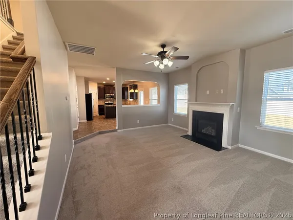 an empty room with windows fireplace and fans
