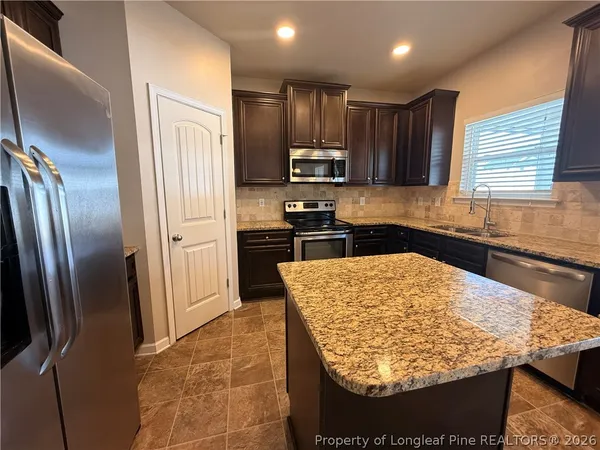 a kitchen with stainless steel appliances kitchen island granite countertop a refrigerator sink and stove
