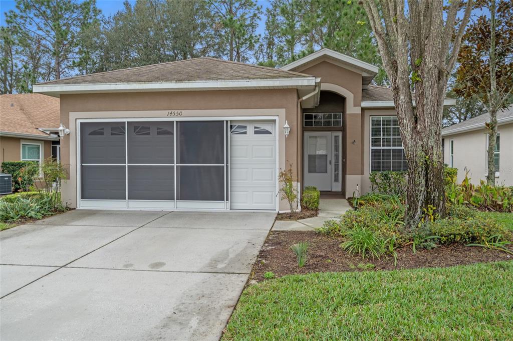 14550 Silversmith Circle Spring Hill, FL 34609 - Photo 1 of 1 a front view of a house with a garden and trees