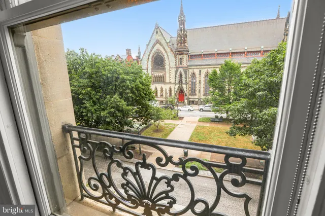 a view of a building with a yard and large trees