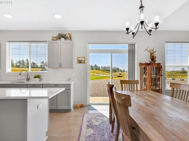 a kitchen with stainless steel appliances granite countertop a sink a stove and a dining table with wooden floor