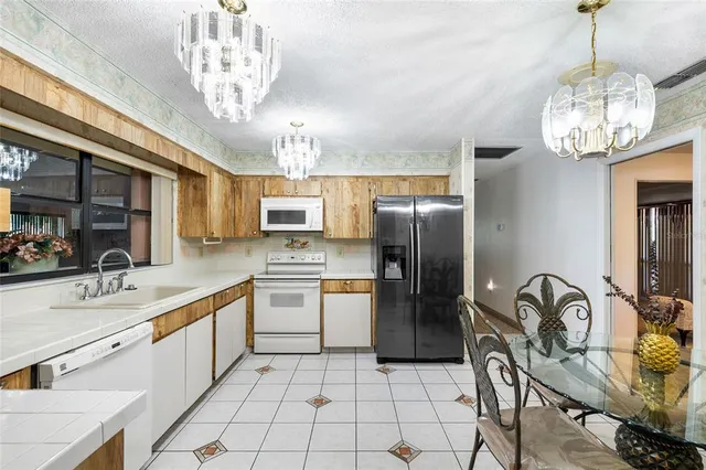 a kitchen with stainless steel appliances granite countertop a sink a stove cabinets and chandelier