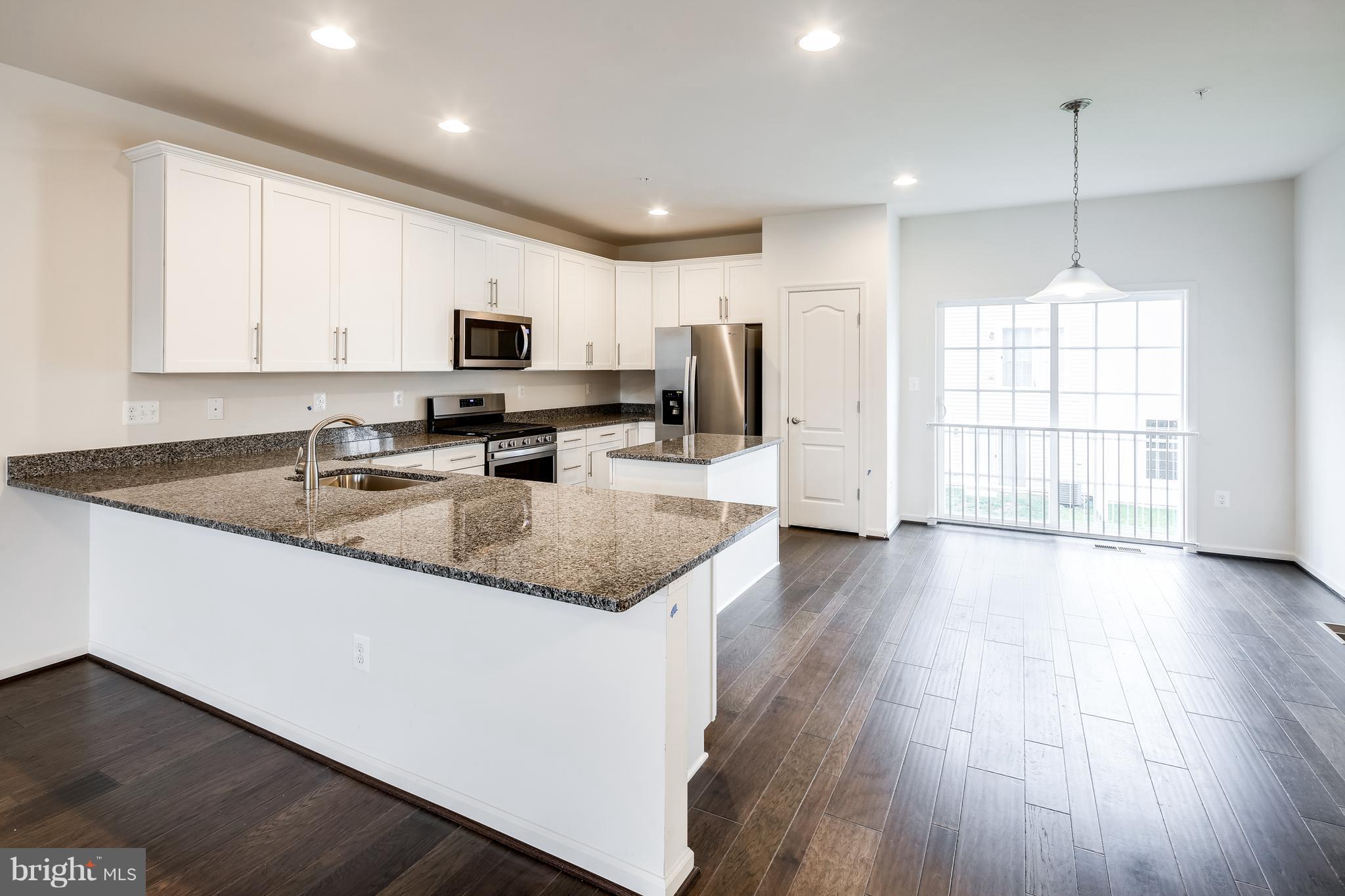 951 Morgan Run Road Middle River, MD 21220 - Photo 5 of 12 a kitchen with stainless steel appliances granite countertop wooden floors a stove a microwave a sink and a center island