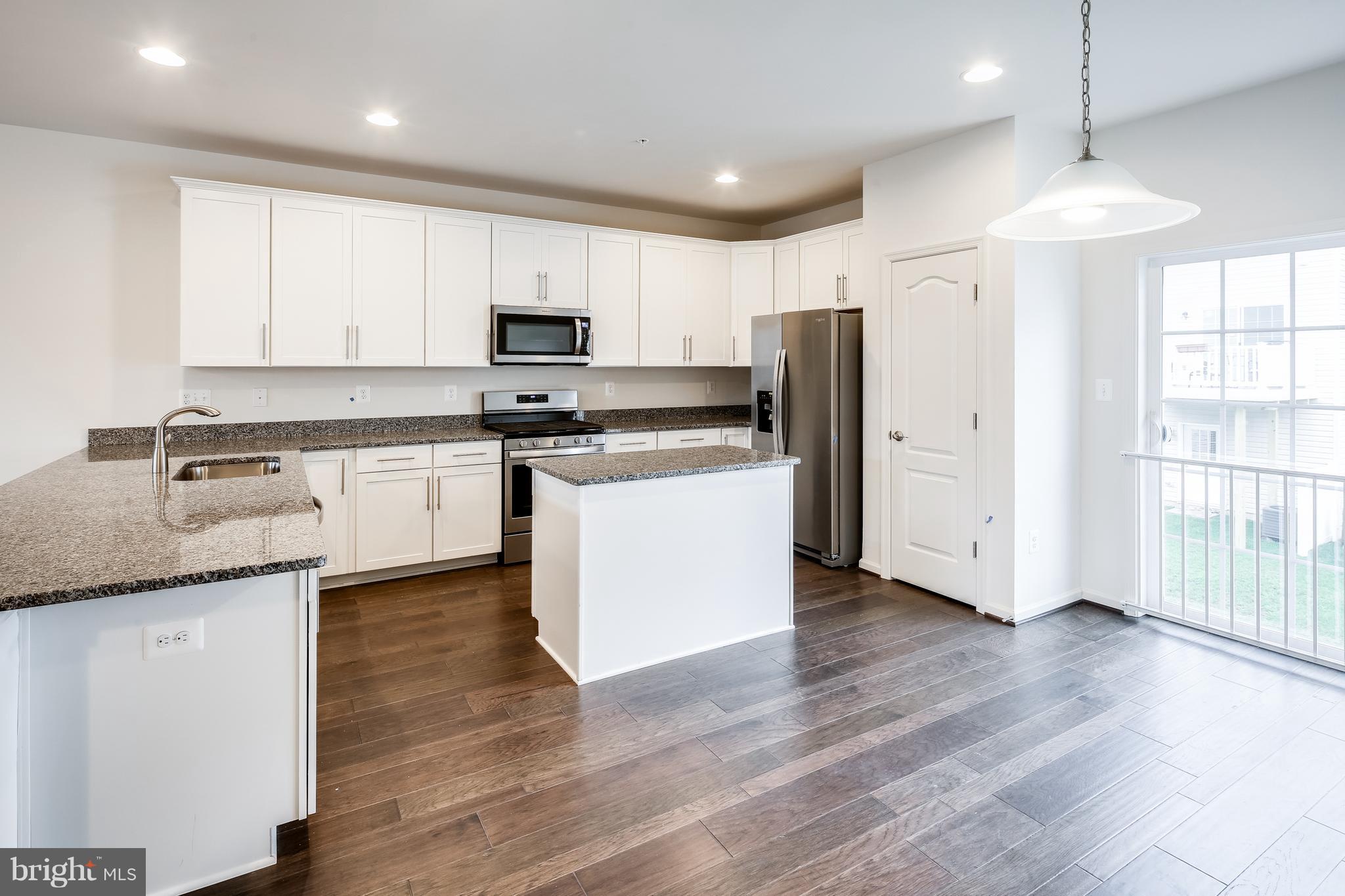 951 Morgan Run Road Middle River, MD 21220 - Photo 9 of 12 a kitchen with stainless steel appliances granite countertop a stove a sink a refrigerator and white cabinets with wooden floor