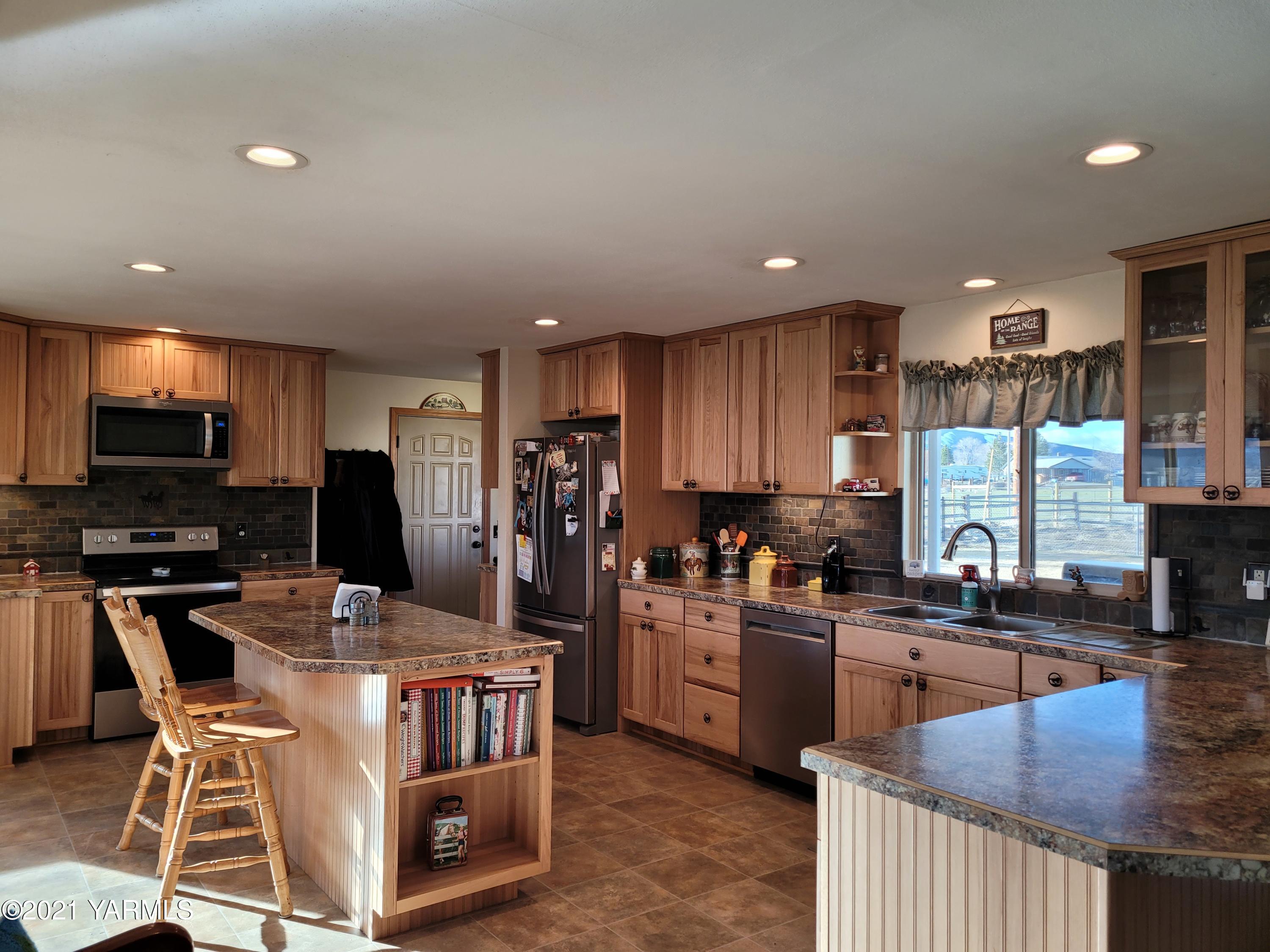 7773 North Wenas Road Selah, WA 98942 - Photo 11 of 45 a kitchen with stainless steel appliances granite countertop a stove top oven a sink a dining table and chairs