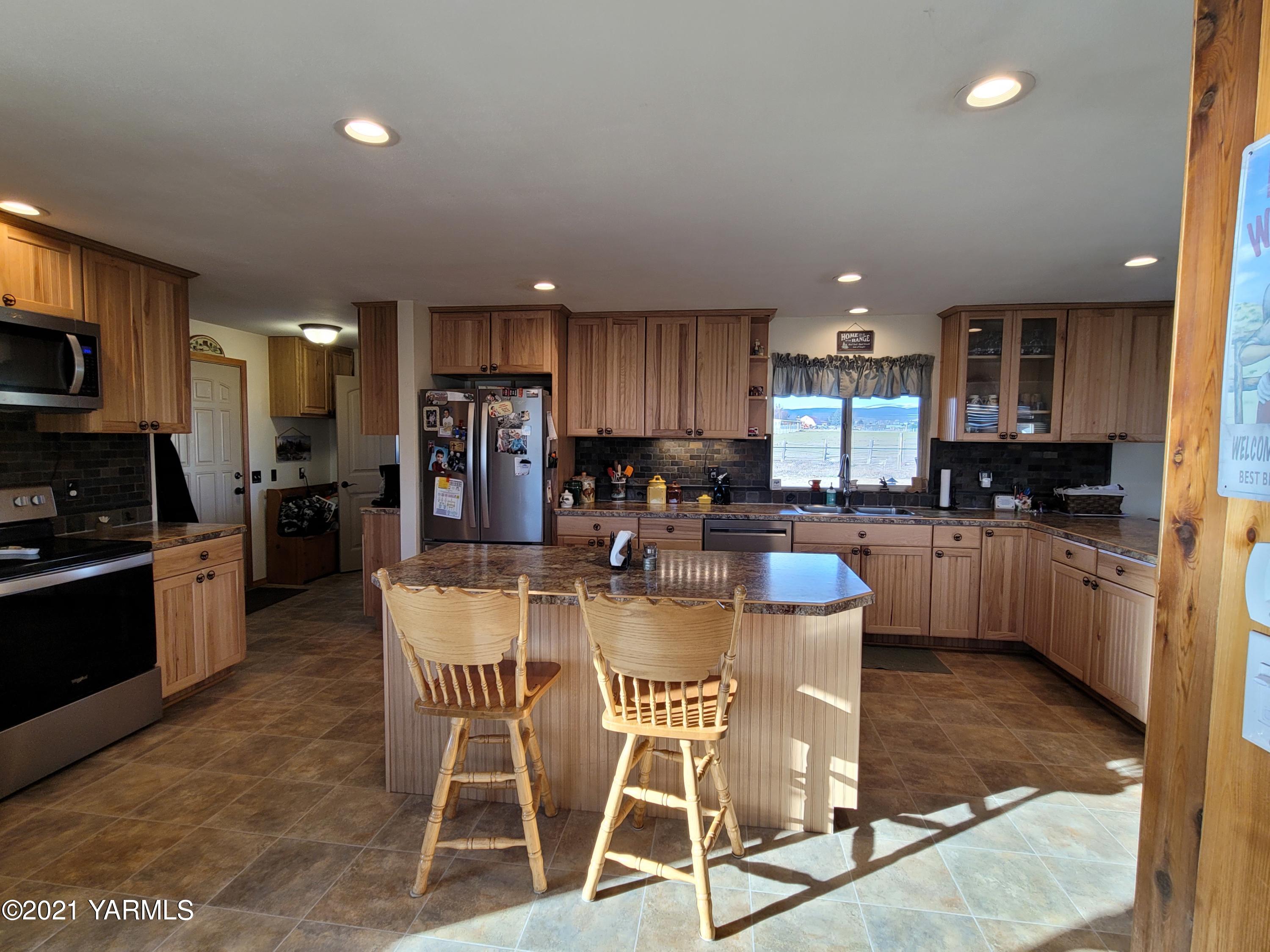 7773 North Wenas Road Selah, WA 98942 - Photo 13 of 45 a kitchen with a dining table cabinets appliances and a counter top