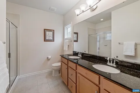 a bathroom with a granite countertop sink a toilet a mirror and a shower