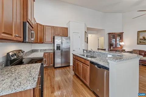 a kitchen with stainless steel appliances granite countertop a refrigerator a stove and a wooden floors