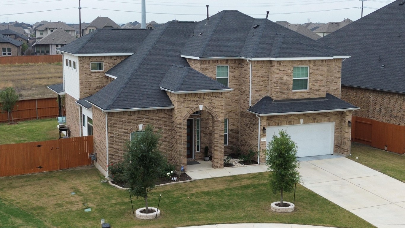 Traditional-style home featuring concrete driveway, brick siding, roof with shingles, and an attached garage