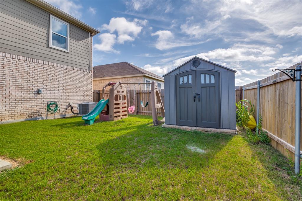 125 Sammy Venus, TX 76084 - Photo 35 of 39 Enclosed backyard featuring a privacy fence, a detached storage shed with double doors, and a natural grass lawn
