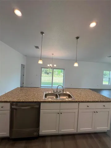 a kitchen with granite countertop a sink and white cabinets