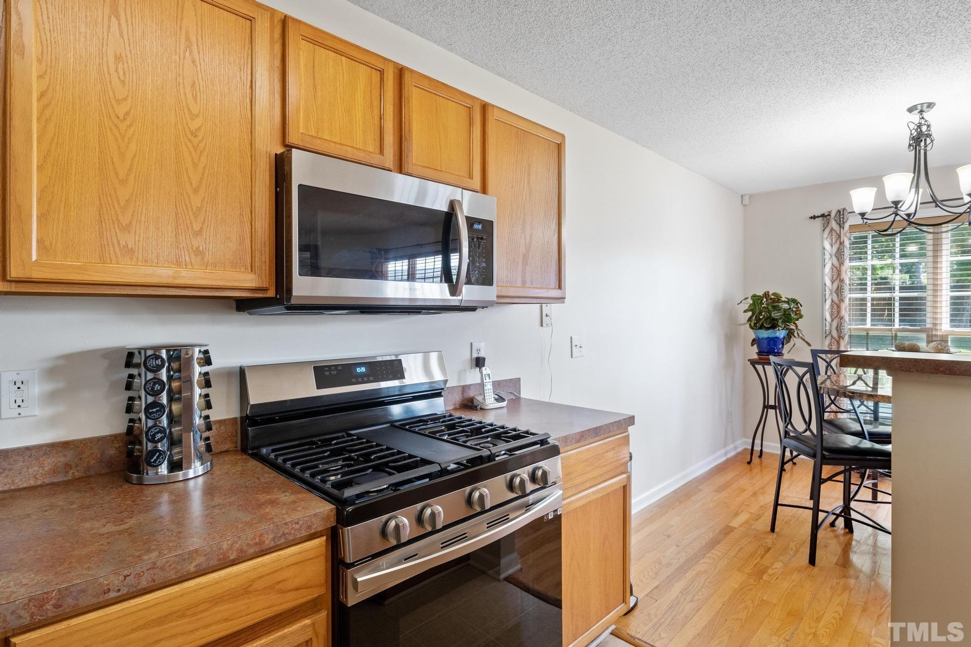 4213 Somerset Valley Lane Raleigh, NC 27616 - Photo 27 of 31 a kitchen with stainless steel appliances granite countertop a stove a microwave and a wooden cabinets