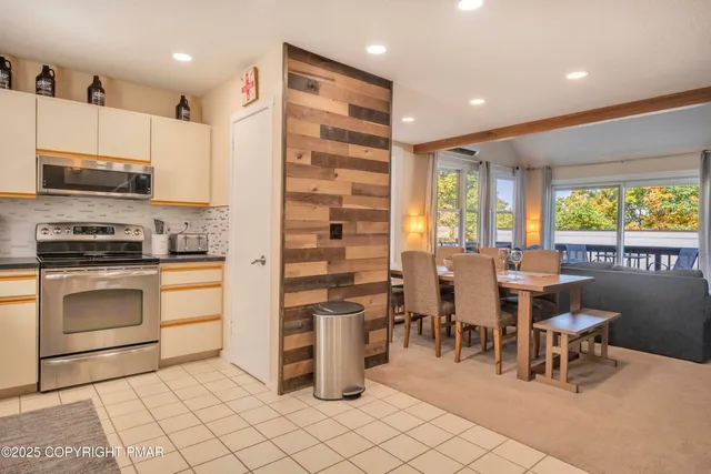 a kitchen with stainless steel appliances kitchen island granite countertop a stove a sink a dining table and chairs