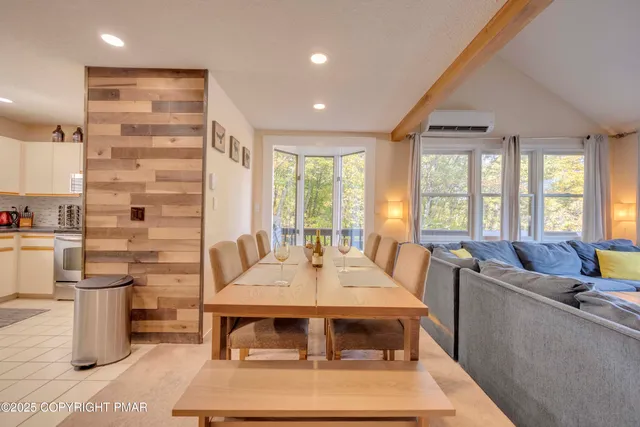 a living room with stainless steel appliances furniture a rug and a large window