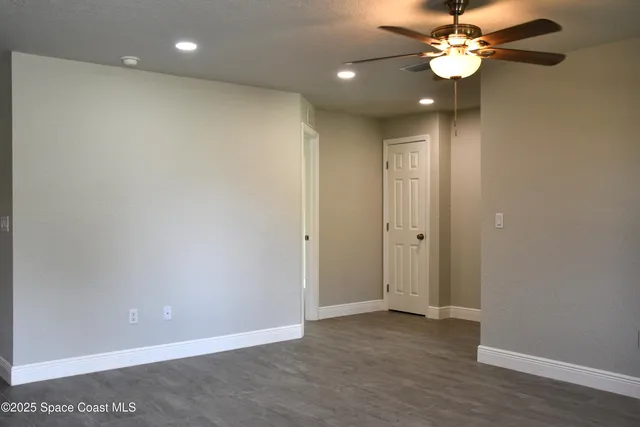 an empty room with wooden floor and a ceiling fan