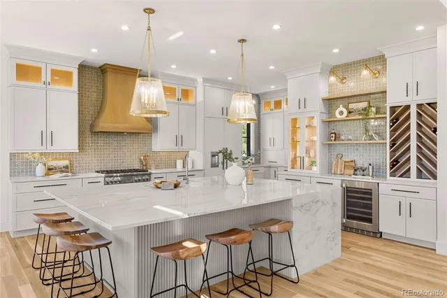 a kitchen with stainless steel appliances granite countertop a sink a stove a refrigerator cabinets and chairs