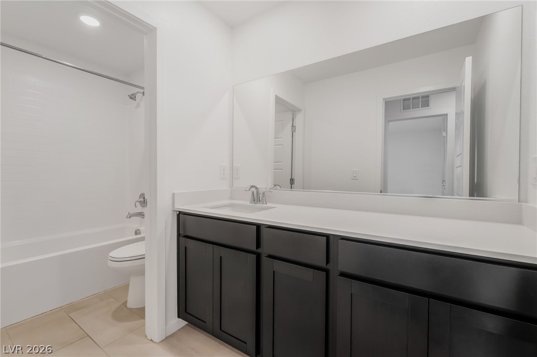 894 Cadence View Way Henderson, NV 89011 - Photo 22 of 23 A well-lit contemporary bathroom features a deep dark wood vanity and a pristine white countertop.