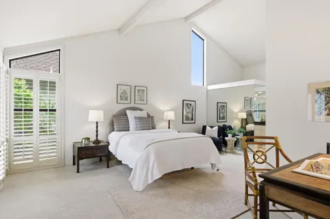 a spacious bedroom with a bed a table and chair