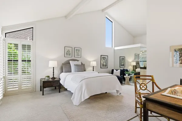 a spacious bedroom with a bed a table and chair