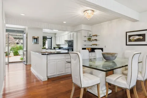 a kitchen with stainless steel appliances granite countertop a stove a refrigerator a kitchen island a dining table and chairs