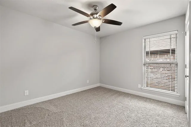 an empty room with a window and a ceiling fan