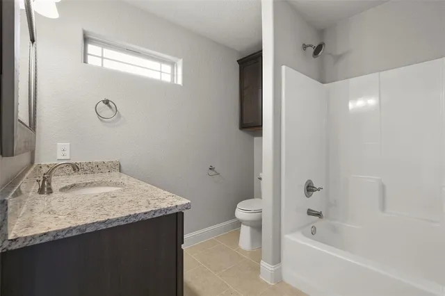 a bathroom with a granite countertop sink a toilet and bathtub