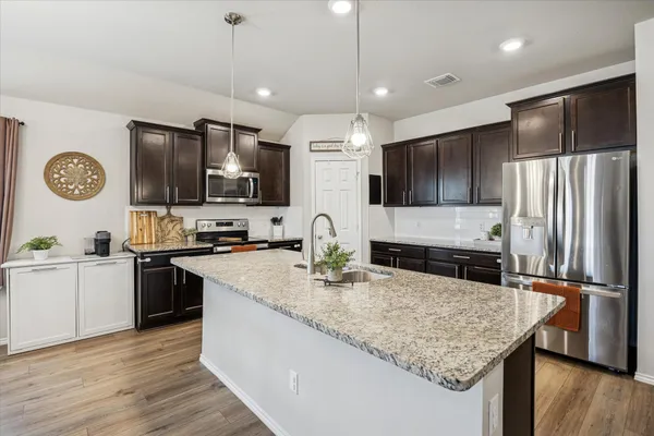 a kitchen with stainless steel appliances granite countertop a sink refrigerator and cabinets