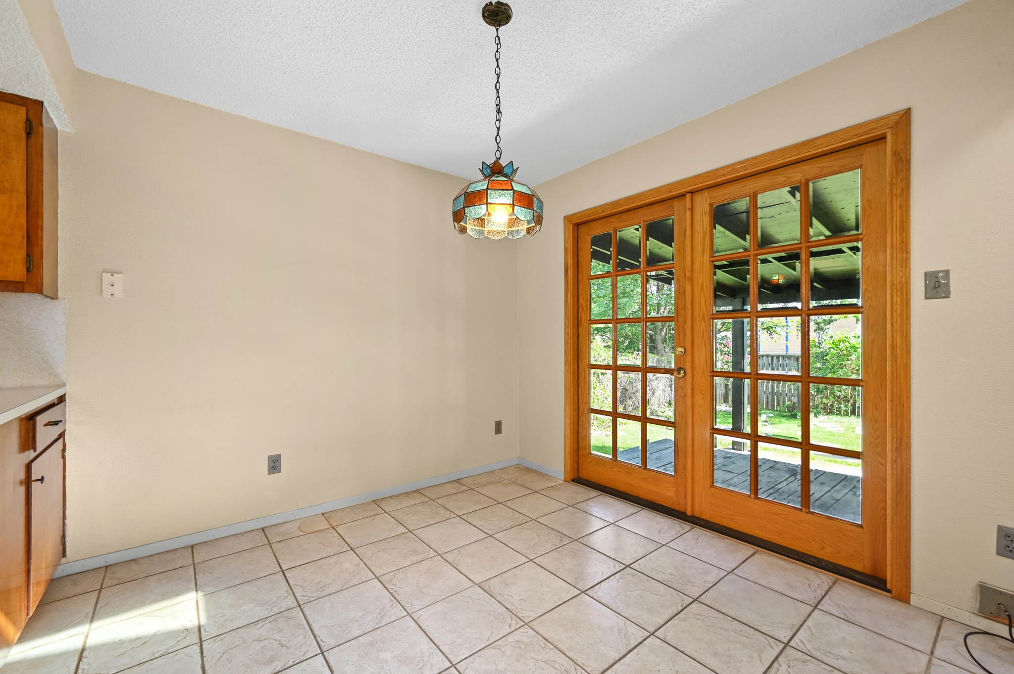 10504 Hard Rock Road Austin, TX 78750 - Photo 10 of 28 French doors open to outdoor space from this well-lit dining area, featuring a decorative overhead light fixture.