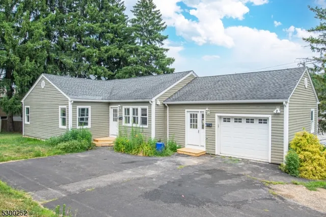 a view of a house with a yard plants and large tree