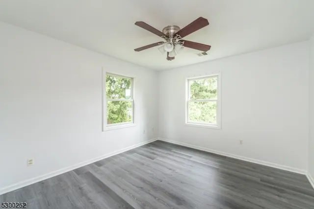 a view of a big room with wooden floor and windows