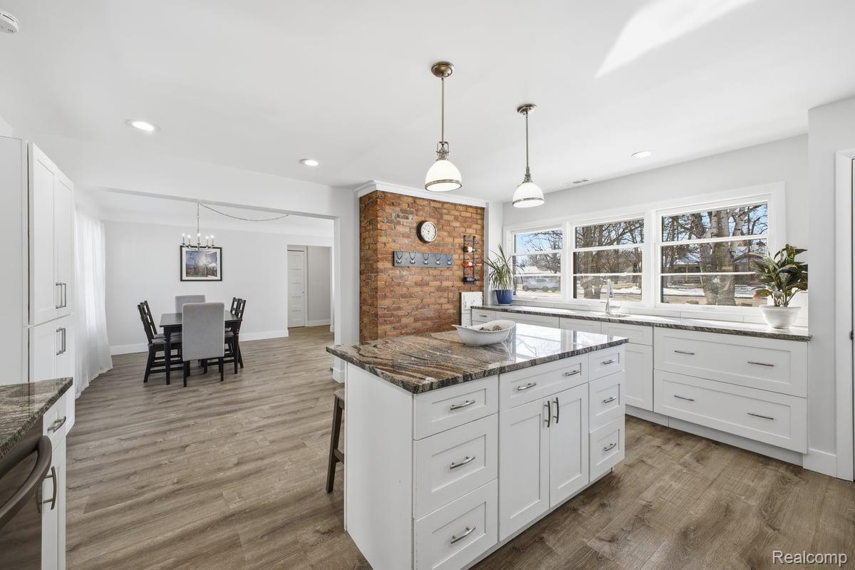 16256 West 13 Mile Road Southfield, MI 48076 - Photo 21 of 30 Kitchen featuring dark stone counters, white cabinets, a breakfast bar area, decorative light fixtures, and dark wood-style floors