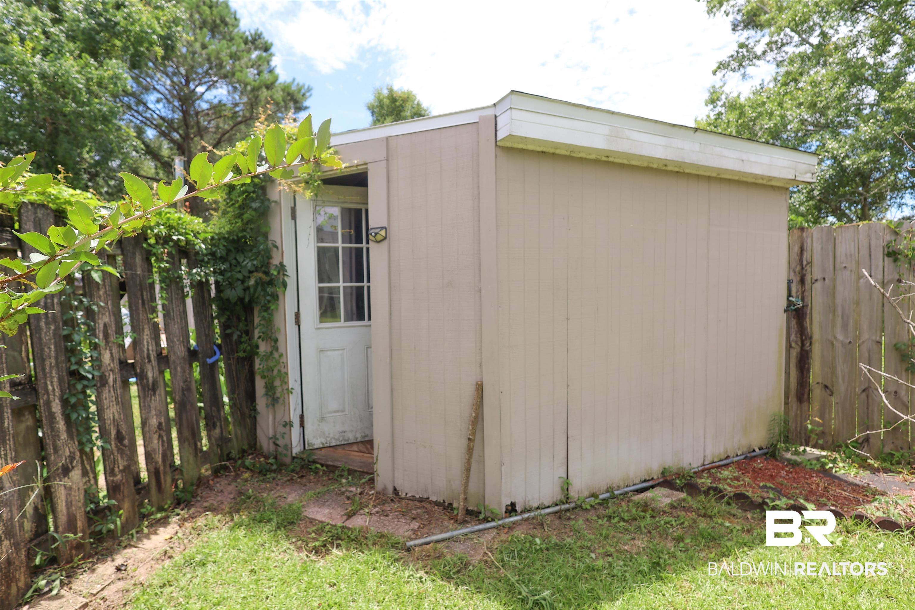 7790 Audubon Drive Foley, AL 36535 - Photo 38 of 39 Detached outdoor storage shed with a panel siding exterior and a white paneled door featuring multiple window panes