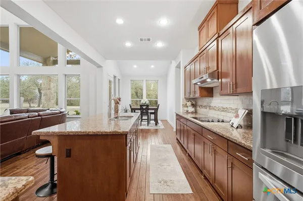 a kitchen with stainless steel appliances granite countertop sink stove top oven and cabinets
