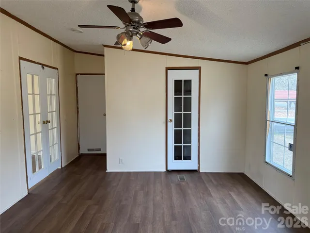 an empty room with wooden floor closet and windows
