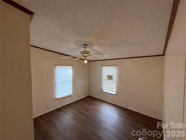 an empty room with wooden floor chandelier fan and windows