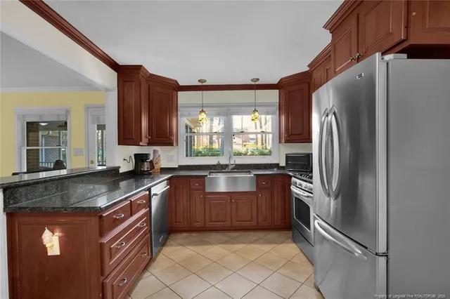 a kitchen with stainless steel appliances granite countertop a refrigerator a sink a stove a washer dryer and a refrigerator