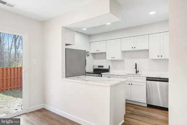 a kitchen with a sink a refrigerator and white cabinets