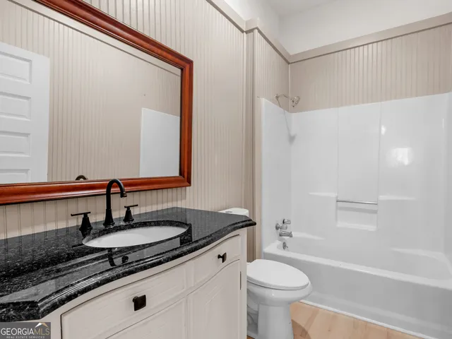 a bathroom with a granite countertop sink toilet a mirror and shower