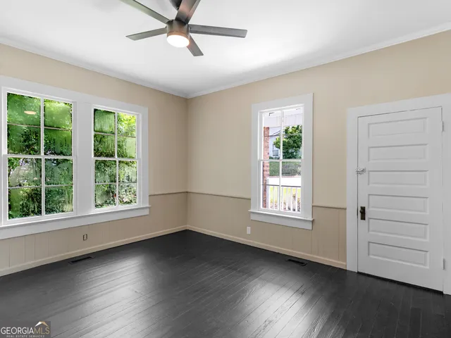 a view of an empty room with wooden floor and a window