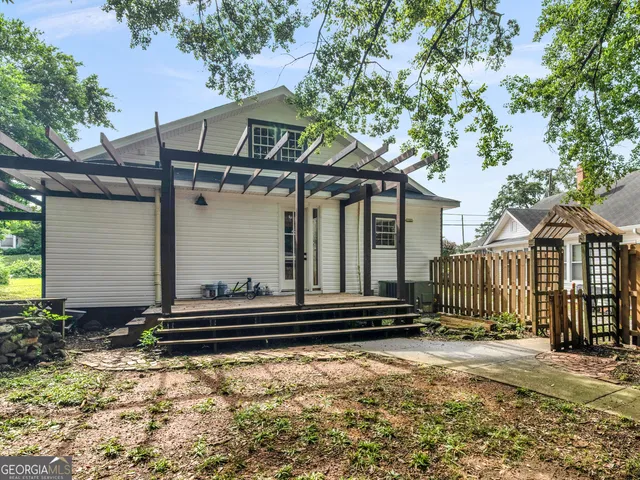 a small white house with a large window and wooden fence
