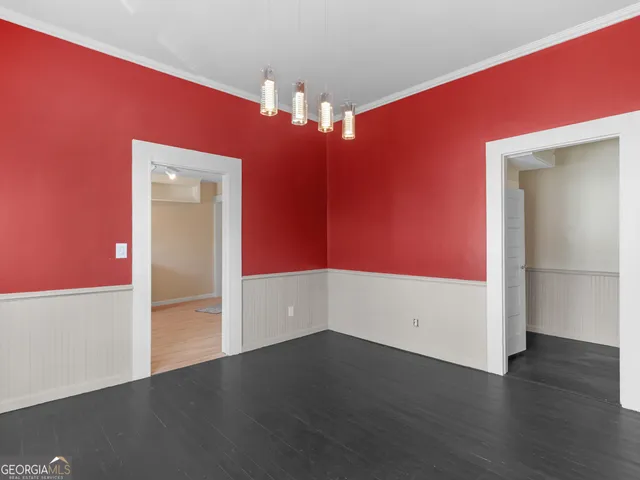 an empty room with wooden floor and chandelier