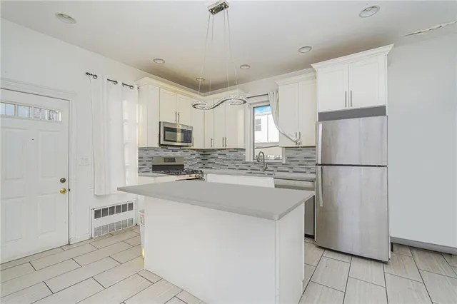 a kitchen with kitchen island a white cabinets and refrigerator
